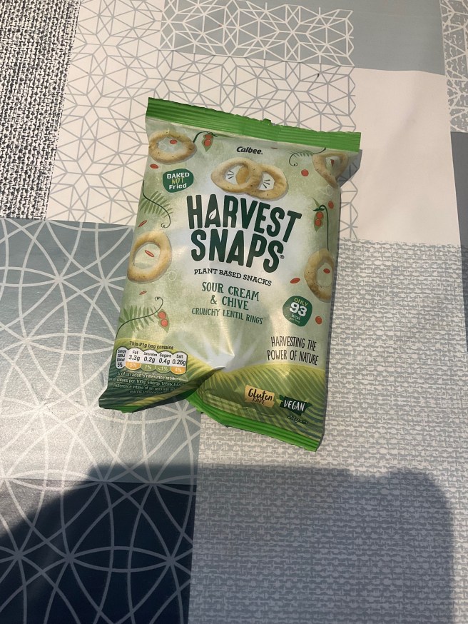 A packet of Harvest Snaps lies on a tablecloth with duck egg colour scheme patterns.