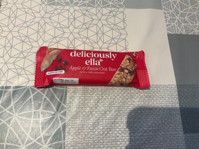 A Deliciously Ella oat bar lies on a tablecloth with various duck egg colour scheme patterns.