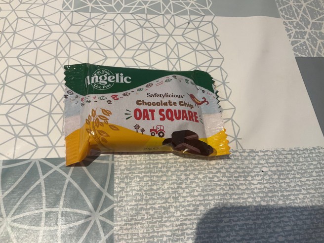 An Angelic Oat Square lies on a tablecloth with various duck egg colour scheme patterns.