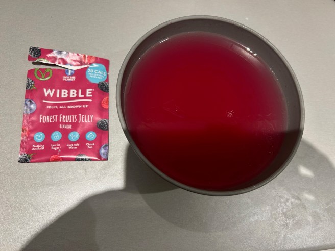 An empty Wibble Jelly packet and a dark grey bowl of the jelly itself sit on a lighter grey worktop.
