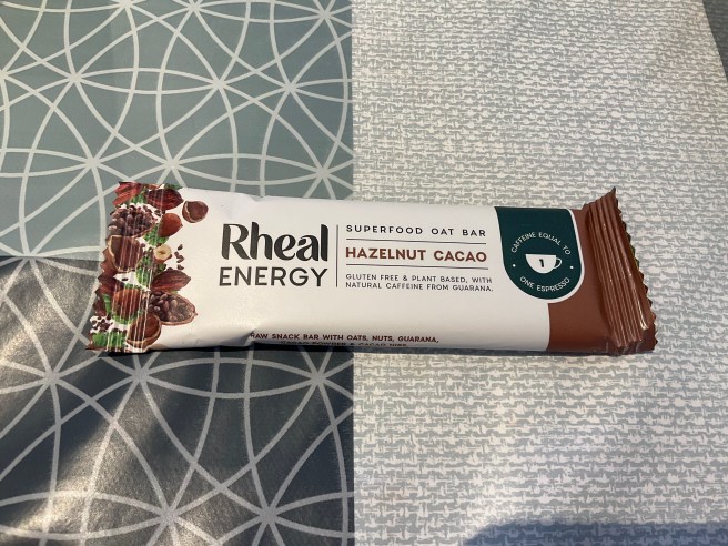 A Rheal Energy bar lies on a tablecloth with duck egg colour scheme patterns.