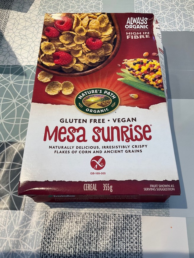 A box of Mesa Sunrise Cereal lies on a tablecloth with duck egg colour scheme patterns.