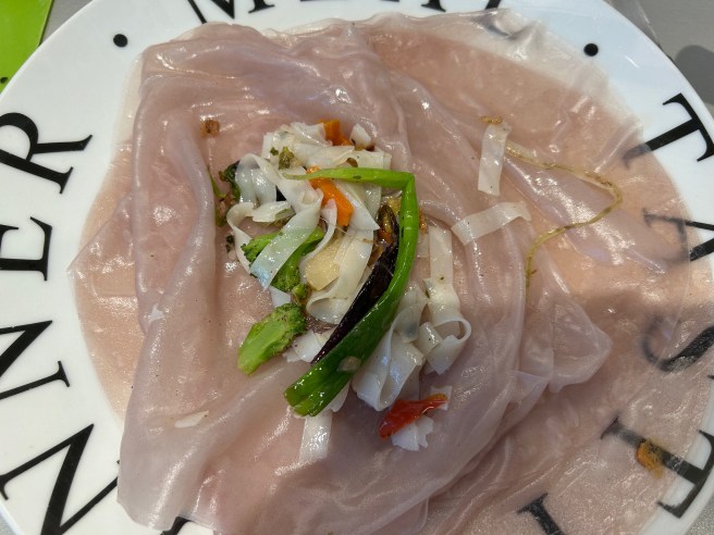 Some rice noodles and vegetables lie on some soaked King Soba Brown Rice Wraps.