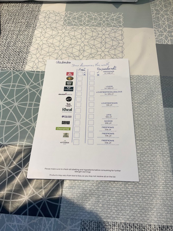 The back of the Love Free From April 2024 leaflet lies on a tablecloth with duck egg colour scheme patterns.